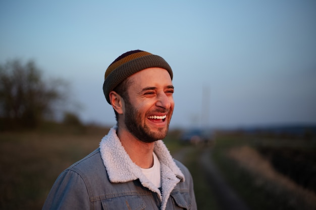 Retrato de jovem hippie sorridente em jaqueta jeans e boné