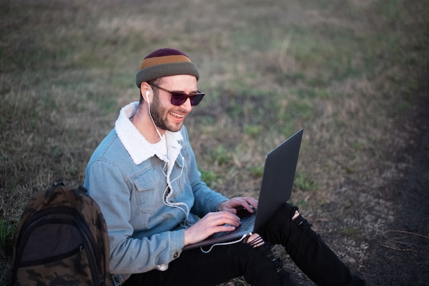 Retrato de jovem hippie usando laptop ao ar livre