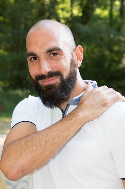 Retrato de jovem homem de barba careca sorrindo no parque