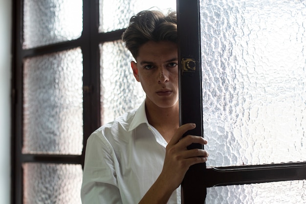 Retrato de jovem homem de camisa branca no interior do apartamento