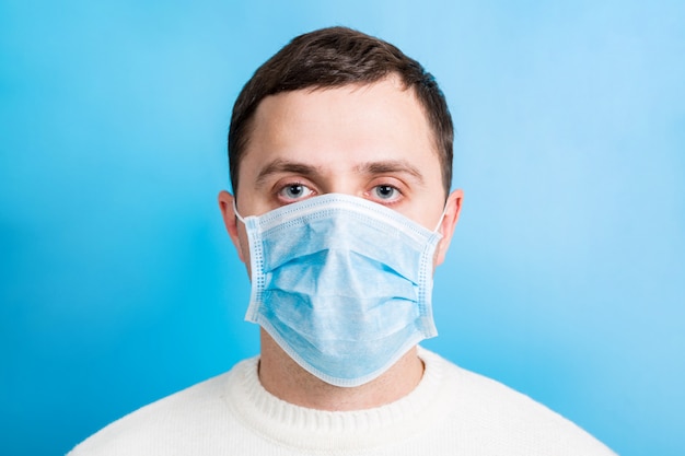 Retrato de jovem homem vestindo máscara médica em azul. conceito de coronavírus. proteção respiratória