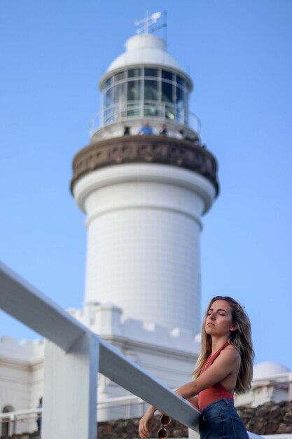 Retrato de jovem inclinado ao lado do farol de Byron Bay Austrália