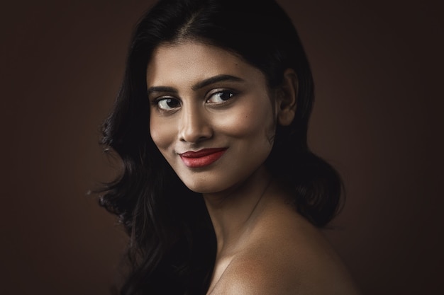 Retrato de jovem indiana com linda maquiagem e penteado na parede marrom
