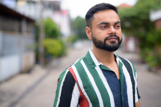 Retrato de jovem indiano barbudo bonito na rua ao ar livre