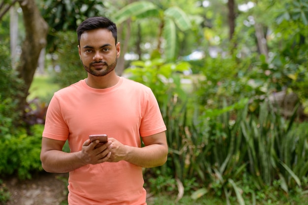 Retrato de jovem indiano barbudo bonito no parque ao ar livre