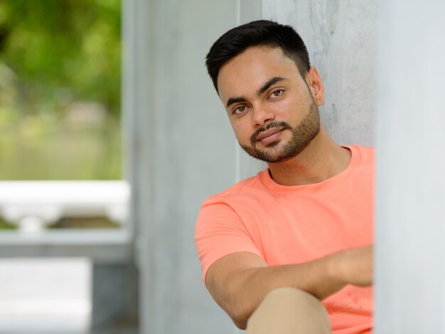 Foto retrato de jovem indiano barbudo bonito no parque ao ar livre