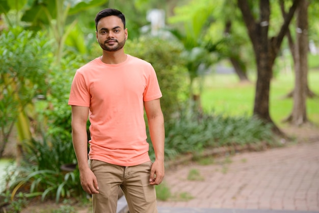 Retrato de jovem indiano barbudo bonito no parque ao ar livre