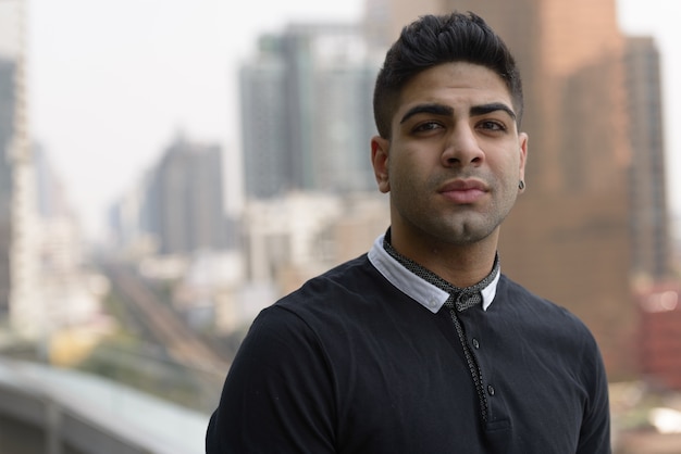 Retrato de jovem indiano bonito contra a vista da cidade