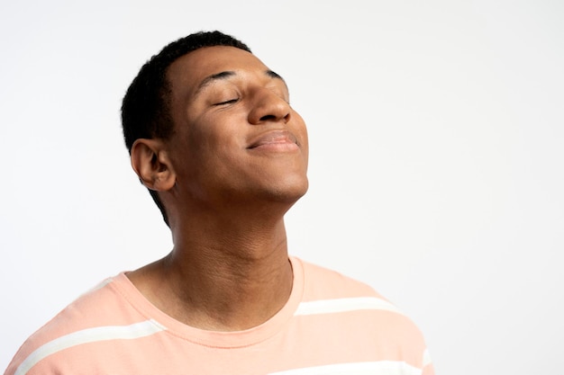 Retrato de jovem latino sorridente posando com os olhos fechados isolados no fundo branco