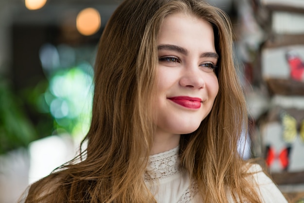 Retrato de jovem linda com maquiagem profissional e penteado no restaurante.