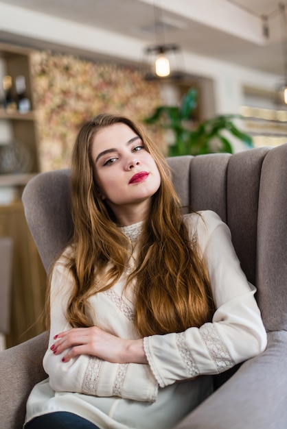 Retrato de jovem linda com maquiagem profissional e penteado no restaurante.