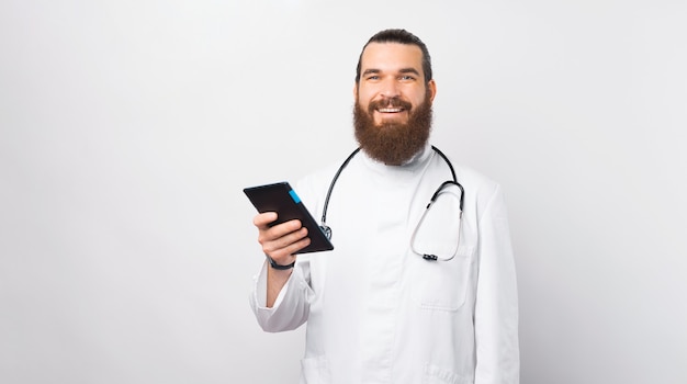 Retrato de jovem médico alegre sorrindo e segurando o tablet