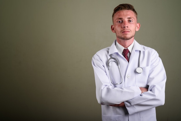 Retrato de jovem médico contra parede colorida