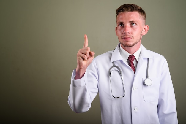 Retrato de jovem médico contra parede colorida