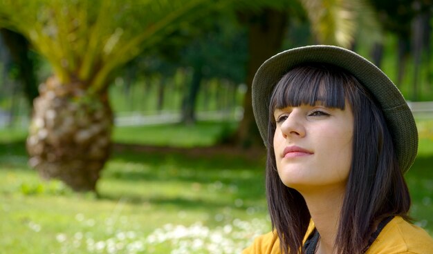 Retrato de jovem menina morena com chapéu de verão no parque