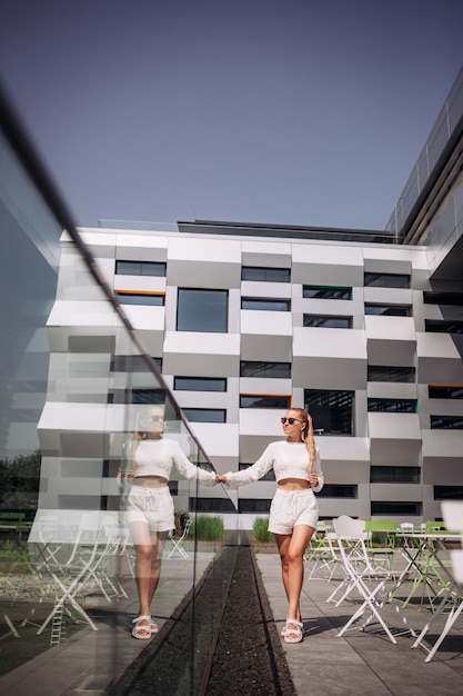 Retrato de jovem modelo de empresária moderna sexy mulher bonita de terno branco posando no fundo da rua moda feminina andando ao ar livre em óculos de sol