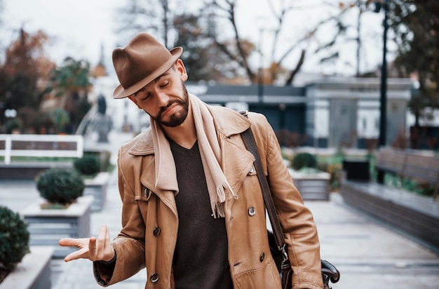 Retrato de jovem modelo masculino em roupas da moda que está ao ar livre na cidade durante o dia