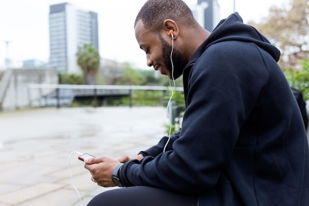 Retrato de jovem moderno usando seu telefone celular na rua.