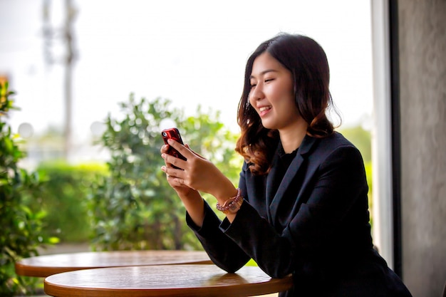 Retrato, de, jovem mulher asiática sorrindo, olha, telefone