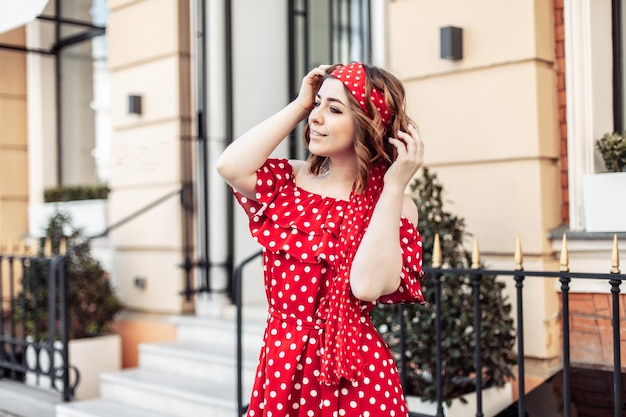 Retrato de jovem mulher bonita em vestido vermelho com pontos polka ao ar livre