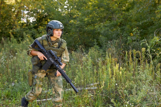 Retrato de jovem mulher com arma em traje militar ao ar livre