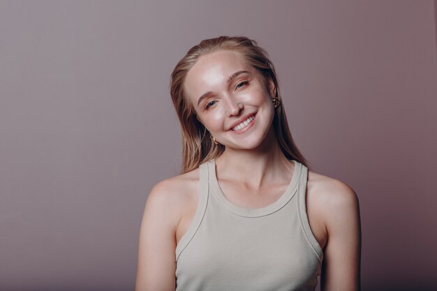 Retrato de jovem mulher europeia 20-25 anos sorrindo. linda garota loira feliz usa camiseta e olha para a câmera. fotos de estúdio isoladas em fundo rosa.