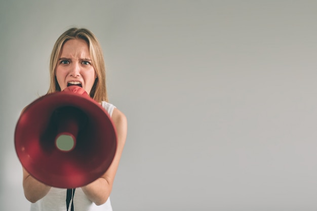 Foto retrato de jovem mulher gritando usando o megafone