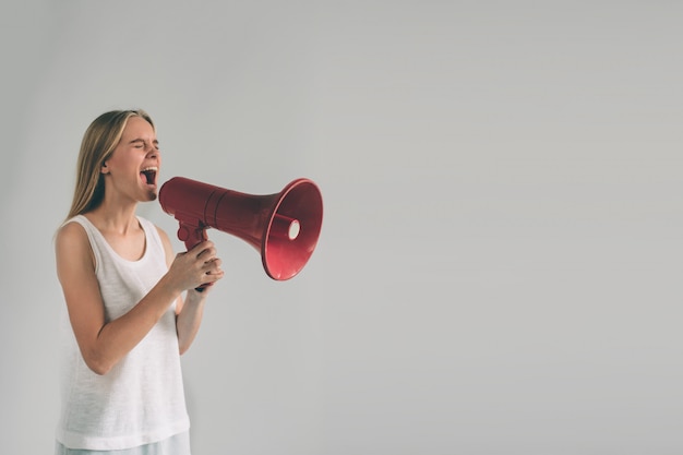 Retrato de jovem mulher gritando usando o megafone