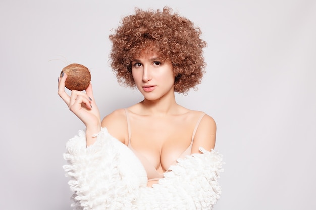 Retrato de jovem negra sorridente. Retrato de uma jovem bonita com maquiagem afro-americana de corte de cabelo e glamour. Tiro do estúdio. Garota atraente usando óculos e coco.