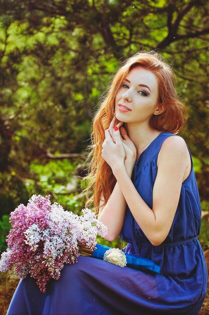 Retrato de jovem no jardim primavera com sardas. florescendo flores roxas. bouquet de lilás