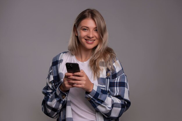 Foto retrato de jovem olhando para a câmera e segurando o telefone