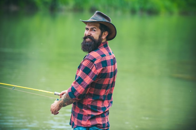Retrato de jovem pescador de pesca com carretel de fiação de vara na margem do rio homem pegando peixe pulli