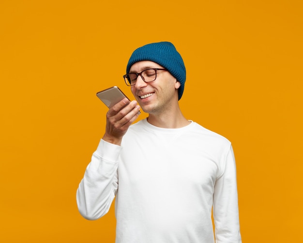 Retrato de jovem positivo gravando mensagem de áudio