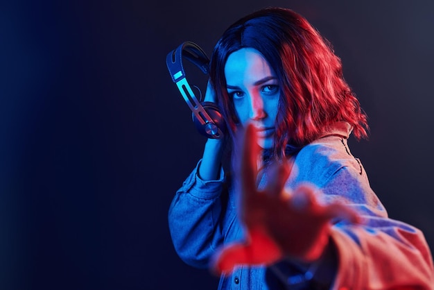 Retrato de jovem que ouve música em fones de ouvido em neon vermelho e azul no estúdio