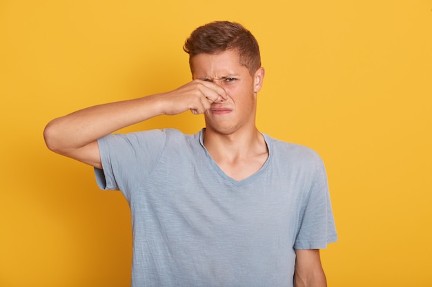 Retrato de jovem rapaz bonito tendo expressão facial desagradável