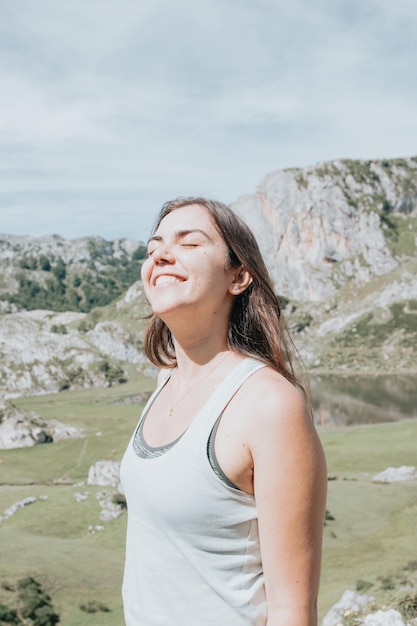 Retrato de jovem rosto sorridente em dia ventoso em pé na montanha - mulher despreocupada. Garota de hipster viajante feliz com cabelo ventoso sorrindo, topo das montanhas. espaço para texto. momento atmosférico.