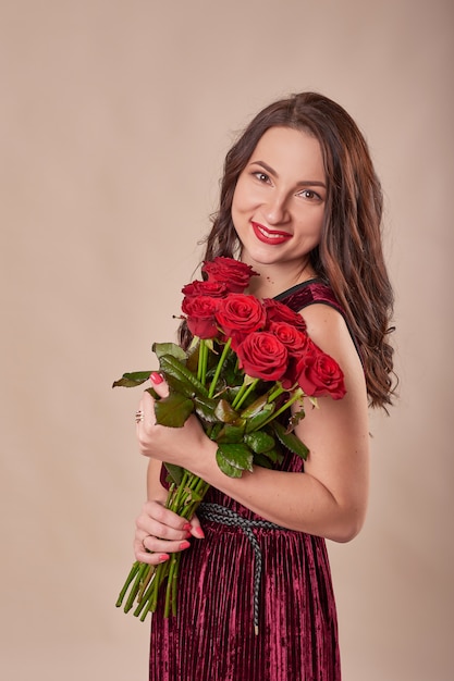 Retrato de jovem satisfeito vestido vermelho com buquê de rosas