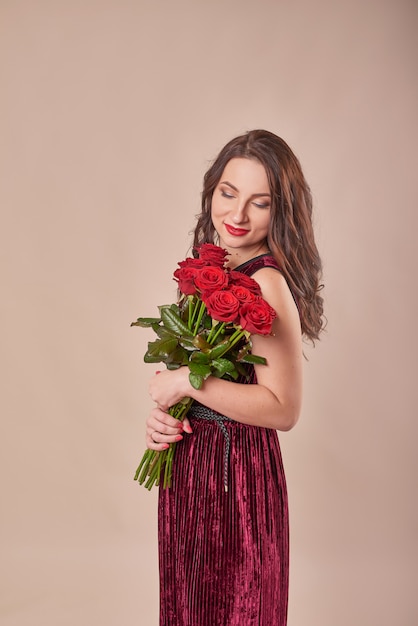 Retrato de jovem satisfeito vestido vermelho com buquê de rosas