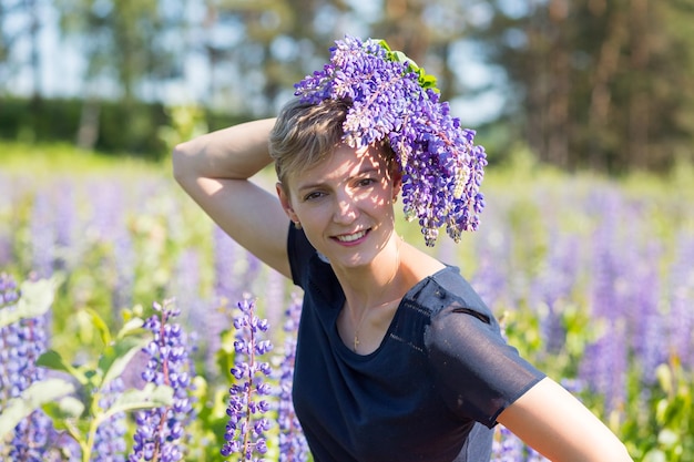 Retrato de jovem segurando buquê de flores de tremoço andando no prado de verão Menina elegante está aproveitando o tempo ensolarado mulher loira com buquê de flores Campo de tremoço Férias de verão