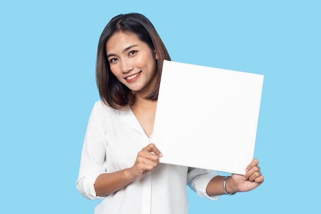 Retrato de jovem segurando o quadro de lona branca vazia para texto ou anúncio isolado em fundo azul