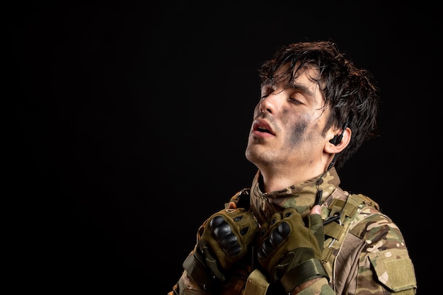 Retrato de jovem soldado cansado de uniforme na parede escura