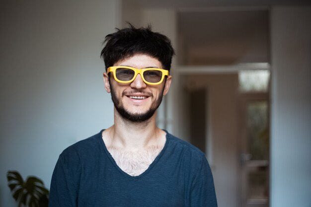 Retrato de jovem sorridente com óculos de sol amarelos.