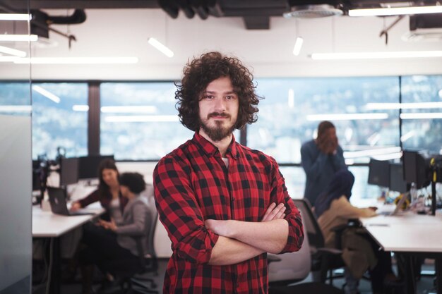 Retrato de jovem sorridente e bem-sucedido desenvolvedor de software masculino em um escritório de inicialização moderna