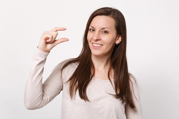 Retrato de jovem sorridente em roupas leves, gesticulando demonstrando tamanho com espaço de trabalho isolado no fundo da parede branca no estúdio. conceito de estilo de vida de emoções sinceras de pessoas. mock up espaço de cópia.