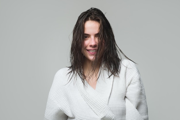 Retrato de jovem sorridente feliz em modelo feminino de roupão de manhã com cabelo molhado e beleza