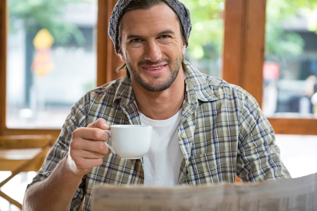 Retrato de jovem sorridente segurando a xícara de café em um café