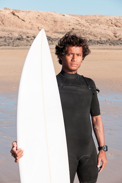 Foto retrato de jovem surfista africano em pé na praia