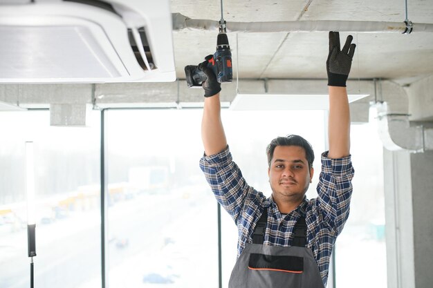 Foto retrato de jovem técnico indiano reparando ar condicionado reparações de ar condicionado