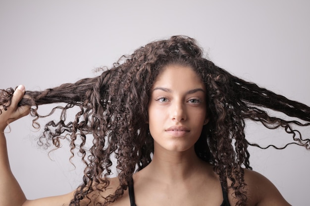 Foto retrato de jovem tocando seu cabelo ondulado