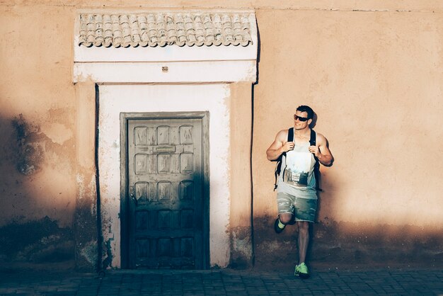 Foto retrato de jovem turista ao lado de uma porta na rua.